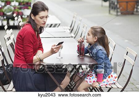 Woman with her daughter sitting in a cafe View Large Photo Image Stock Image - Woman with her daughter sitting in a cafe. Fotosearch