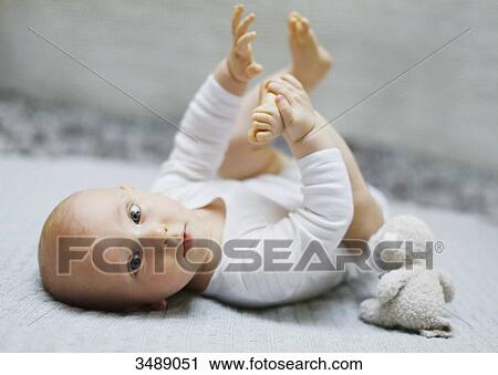 8 months baby boy lying down and playing with his feet View Large Photo Image Stock Image - 8 months baby boy lying down and playing with his feet. Fotosearch