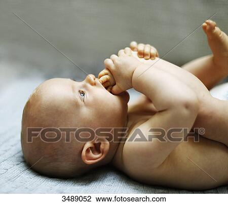 8 months baby boy lying down and playing with his feet View Large Photo Image Stock Image - 8 months baby boy lying down and playing with his feet. Fotosearch