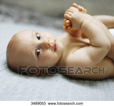 8 months baby boy lying down and playing with his feet View Large Photo Image Stock Image - 8 months baby boy lying down and playing with his feet. Fotosearch