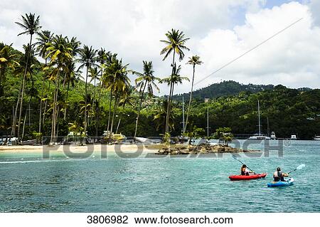 Stock Image - A couple in a canoes at MArigot Bay, Sainte-Lucia, West Indies. Fotosearch