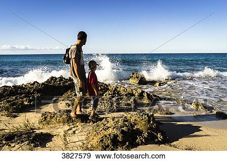 Stock Photo - A father and his son in front of the sea, Saint-Louis, Marie-Galante, Guadeloupe, France. Fotosearch