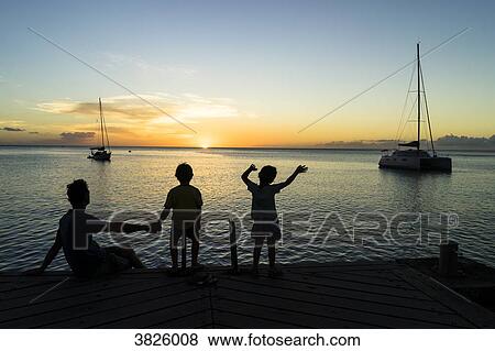 Stock Photo - A father and his two sons looking at the sunset, Saint-Pierre, Martinique, France. Fotosearch