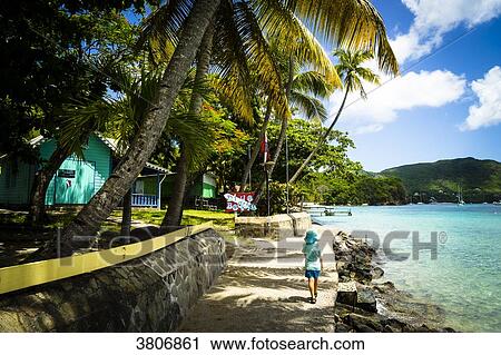 Stock Image - A kid walking along the sea, Port Elizabeth, Bequia, Saint-Vincent and the Grenadines, West Indies. Fotosearch