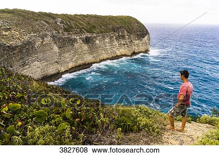 Stock Photo - A man in front of the Pointe Cavale's cliff, Capesterre, Marie Galante, Guadeloupe. Fotosearch