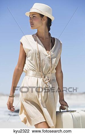 Beautiful woman carrying a suitcase on the beach View Large Photo Image Stock Image - Beautiful woman carrying a suitcase on the beach. Fotosearch