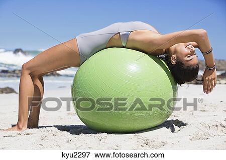 Beautiful woman exercising with fitness ball on the beach View Large Photo Image Stock Photo - Beautiful woman exercising with fitness ball on the beach. Fotosearch