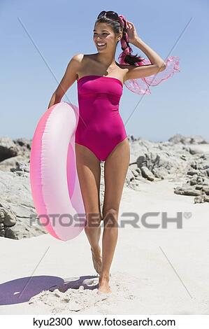 Stock Image - Beautiful woman holding an inflatable ring on the beach. Fotosearch