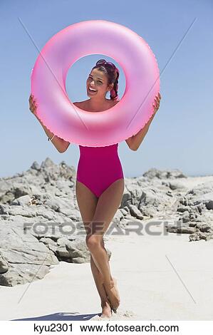 Beautiful woman looking through an inflatable ring on the beach View Large Photo Image Stock Image - Beautiful woman looking through an inflatable ring on the beach. Fotosearch