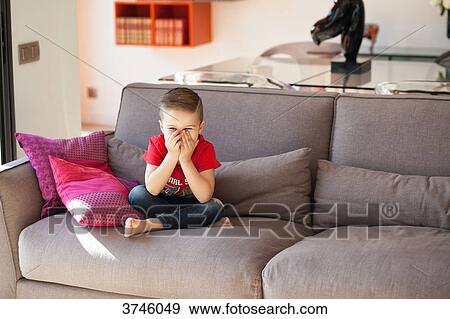 Boy laughing, sitting on a couch View Large Photo Image Stock Photo - Boy laughing, sitting on a couch. Fotosearch