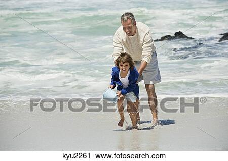 Stock Image - Boy playing with his grandfather on the beach. Fotosearch