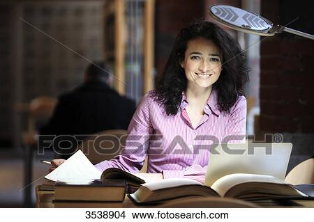 Brown-haired young woman in a library. View Large Photo Image Picture - Brown-haired young woman in a library.. Fotosearch