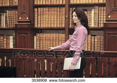 Brown-haired young woman in a library. View Large Photo Image Stock Photo - Brown-haired young woman in a library.. Fotosearch