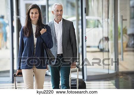 Business couple pulling suitcases in a hotel lobby View Large Photo Image Stock Image - Business couple pulling suitcases in a hotel lobby. Fotosearch