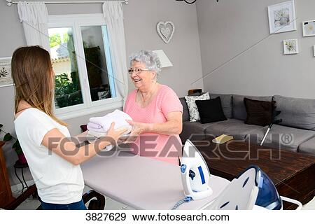 Cheerful young girl ironing and helping with household chores elderly woman at home. View Large Photo Image Stock Photo - Cheerful young girl ironing and helping with household chores elderly woman at home.. Fotosearch