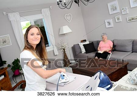 Cheerful young girl ironing and helping with household chores elderly woman at home. View Large Photo Image Stock Photograph - Cheerful young girl ironing and helping with household chores elderly woman at home.. Fotosearch