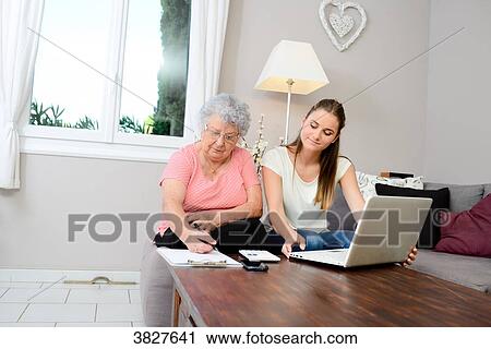 Cheerful young woman helping old person doing paperwork and telephone call. View Large Photo Image Stock Image - Cheerful young woman helping old person doing paperwork and telephone call.. Fotosearch
