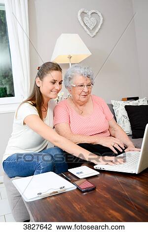 Cheerful young woman helping old person doing paperwork and telephone call. View Large Photo Image Stock Image - Cheerful young woman helping old person doing paperwork and telephone call.. Fotosearch