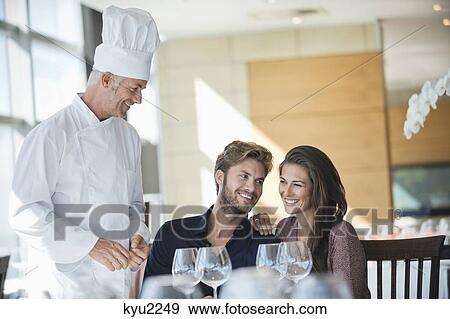 Chef talking to couple at restaurant View Large Photo Image Stock Photo - Chef talking to couple at restaurant. Fotosearch