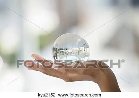 Stock Image - Close-up of a person's hand holding a crystal ball. Fotosearch