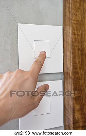 Stock Image - Close-up of a person's hand pressing a light switch. Fotosearch