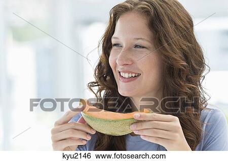 Close-up of a smiling woman eating melon View Large Photo Image Stock Photograph - Close-up of a smiling woman eating melon. Fotosearch