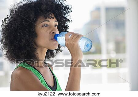 Stock Image - Close-up of a woman drinking water from a bottle. Fotosearch