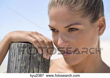 Stock Photo - Close-up of a woman near a wooden post. Fotosearch