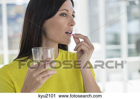 Stock Image - Close-up of a woman taking medicine. Fotosearch