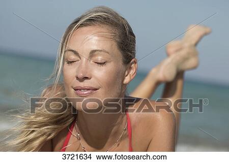 Close-up of smiling blond close eyes woman lying on the sand View Large Photo Image Picture - Close-up of smiling blond close eyes woman lying on the sand. Fotosearch