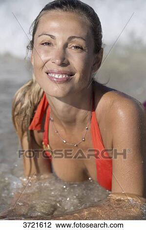 Stock Image - Close-up of smiling blond woman lying in water. Fotosearch