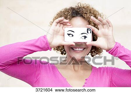 Close-up of smiling Malagasy woman with phone in front of eyes View Large Photo Image Picture - Close-up of smiling Malagasy woman with phone in front of eyes. Fotosearch