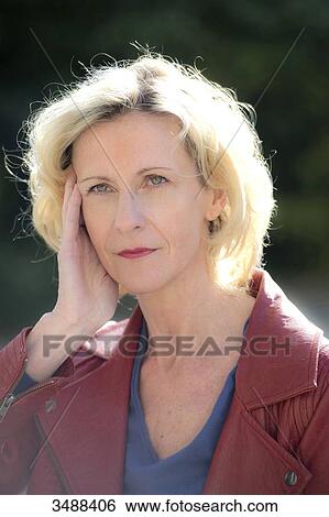 Stock Photograph - Corinne, 50-year-old woman, one hand on her face, pensive.. Fotosearch
