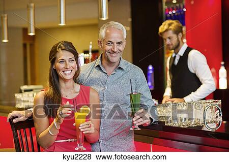 Couple enjoying drinks at the bar counter View Large Photo Image Stock Photo - Couple enjoying drinks at the bar counter. Fotosearch