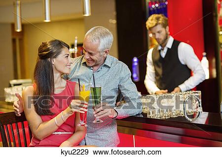 Stock Photo - Couple enjoying drinks at the bar counter. Fotosearch