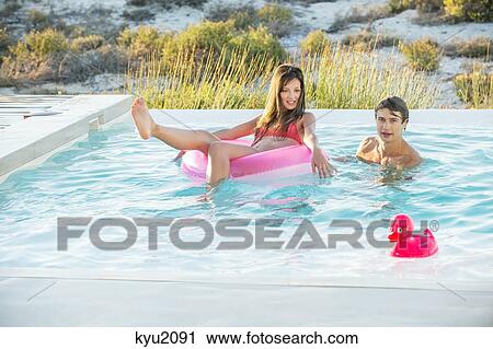 Stock Image - Couple enjoying in a swimming pool on the beach. Fotosearch