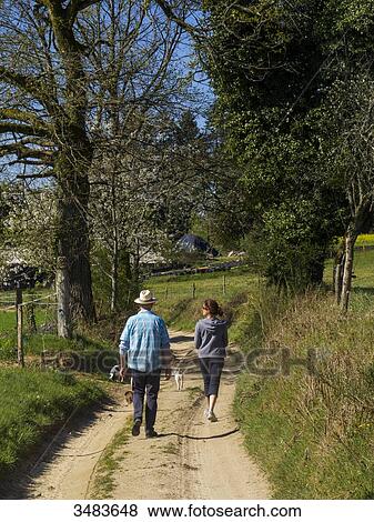 Stock Photo - Couple having a walk in the country with their dogs. Fotosearch