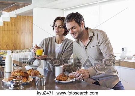 Couple having breakfast at a kitchen counter View Large Photo Image Stock Image - Couple having breakfast at a kitchen counter. Fotosearch