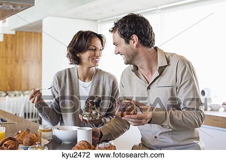 Stock Image - Couple having breakfast at a kitchen counter. Fotosearch