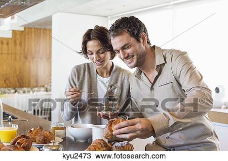 Stock Image - Couple having breakfast at a kitchen counter. Fotosearch