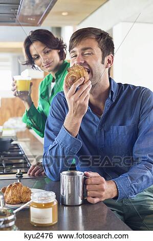 Couple having breakfast at a kitchen counter View Large Photo Image Stock Photograph - Couple having breakfast at a kitchen counter. Fotosearch