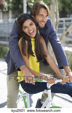 Couple riding a bicycle and smiling View Large Photo Image Stock Image - Couple riding a bicycle and smiling. Fotosearch