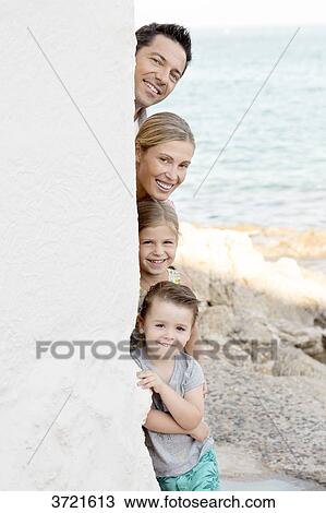 Stock Image - Family portrait, parents with their children stacked behind a wall. Fotosearch