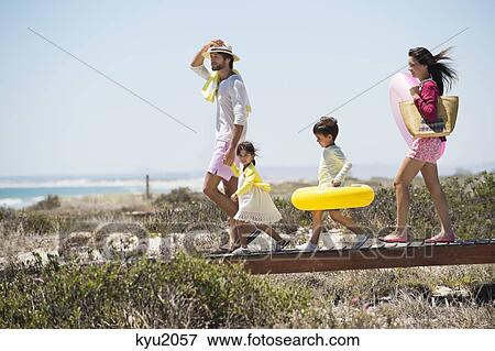 Stock Photo - Family walking on a boardwalk on the beach. Fotosearch