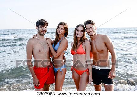 Stock Image - France, 2 young couples friends posing in front of the sea.. Fotosearch