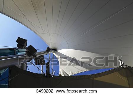 Stock Image - France, bottom view of a mat supporting sail shaped tarp. Blue sky. Fotosearch