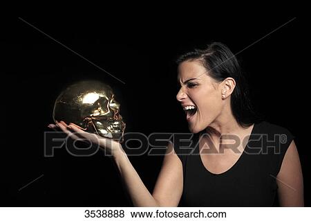 Stock Photo - France, brown young woman in studio with skull. Fotosearch