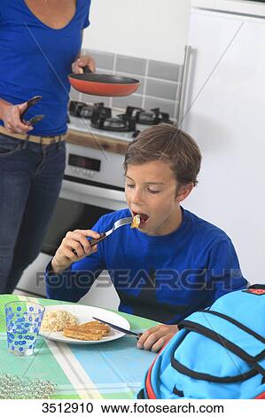 Stock Image - France, child eating breaded fish. Fotosearch