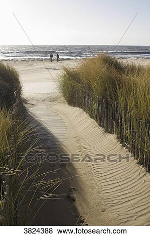 Stock Photo - France, La Bernerie-en-Retz, two persons on the beach in winter.. Fotosearch