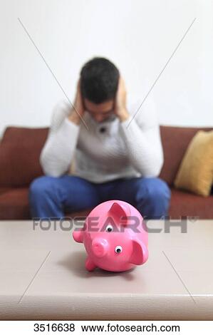 Stock Photo - France, man at home, piggybank. Fotosearch